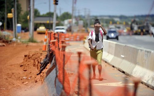  Pedestrian on temporary pedestrian path along North Tryon Street near University Pointe Boulevard. Photo: Nancy Pierce 6-11-15 With sidewalks uprooted, a pedestrian endures 95-degree heat, bright sun and dust on the temporary pedestrian path along North Tryon Street near University Pointe Boulevard. Photo: Nancy Pierce