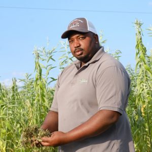 Davon Goodwin is manager of Sandhills AGInnovation Center in Ellerbee, NC  Behind him is a hemp cover crop. Photo: Nancy Pierce